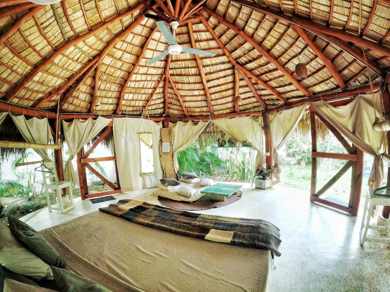 Casa Picaflor: room under a thatched roof with a king bed and a hanging chair